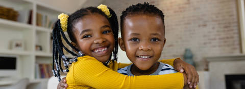 Foster boy and girl smiling in a living room scene