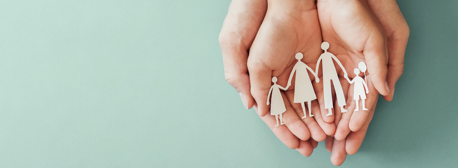 Hands holding paper cut out of family