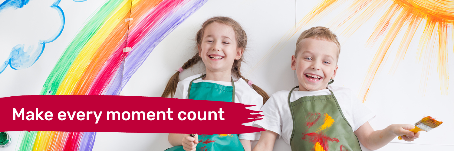 Two foster children with paint brushes painting a rainbow and sun