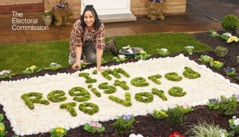 Lady crouched down gardening. Flowers say I'm registered to vote