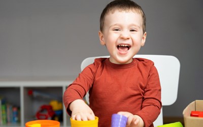Funded childcare for 2 year olds - child sat in sunshine smiling