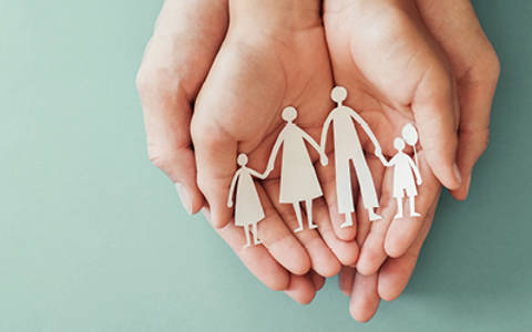 Hands holding paper cut out of family