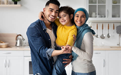 Foster parents stood holding their foster child in their home